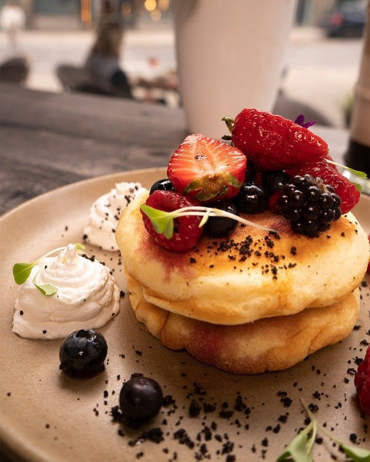 Uma pilha de panquecas com frutas e chantilly por cima