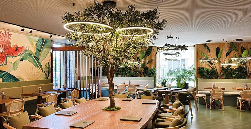 Duas pessoas seguram taças de martini em frente a uma cerca de corda.