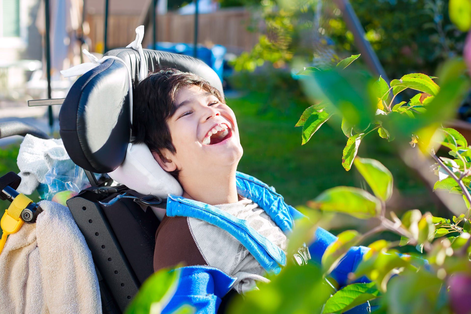 Disabled-biracial-ten-year-old-boy-in-wheelchair-relaxed-and-laughing-in-back-yard