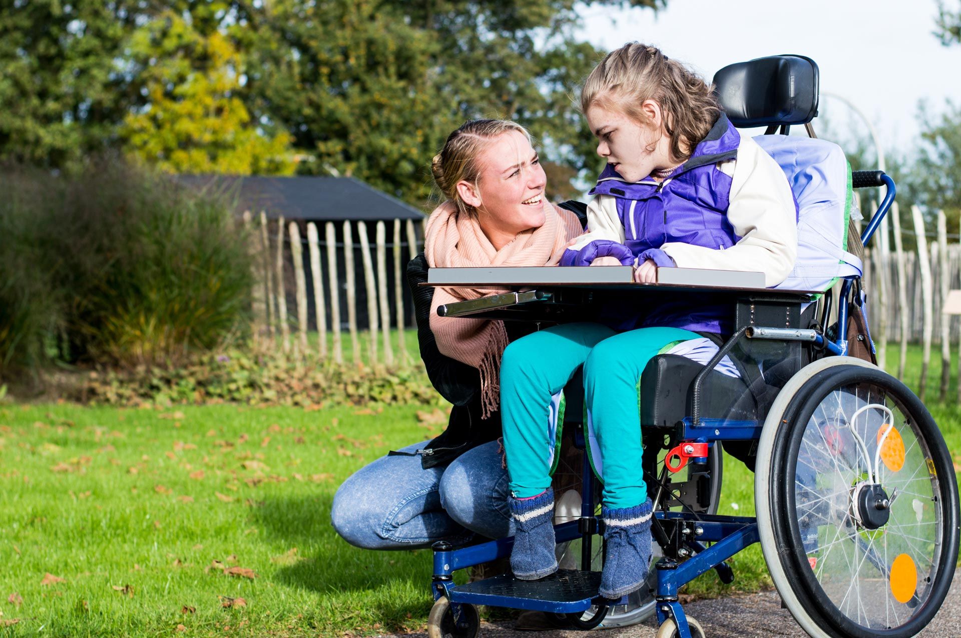 disabled-child-in-a-wheelchair-relaxing-outside-with-a-care-assistant-working-with-disability-340446914