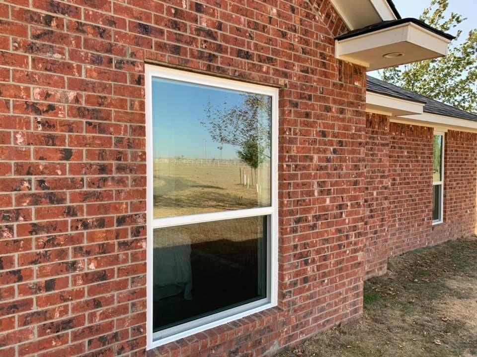 A red brick house with a white window on the side.