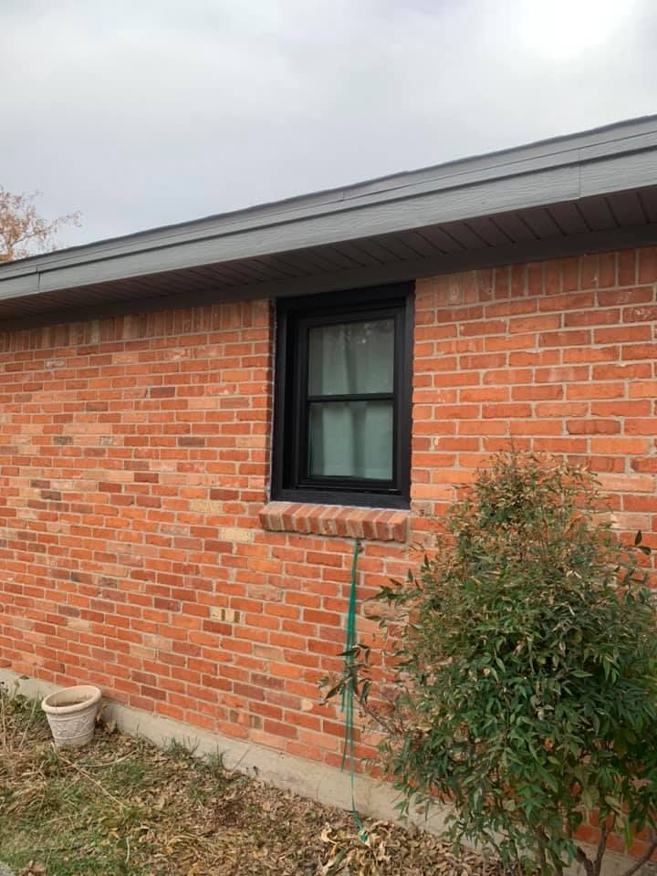 A brick house with a black window on the side of it.