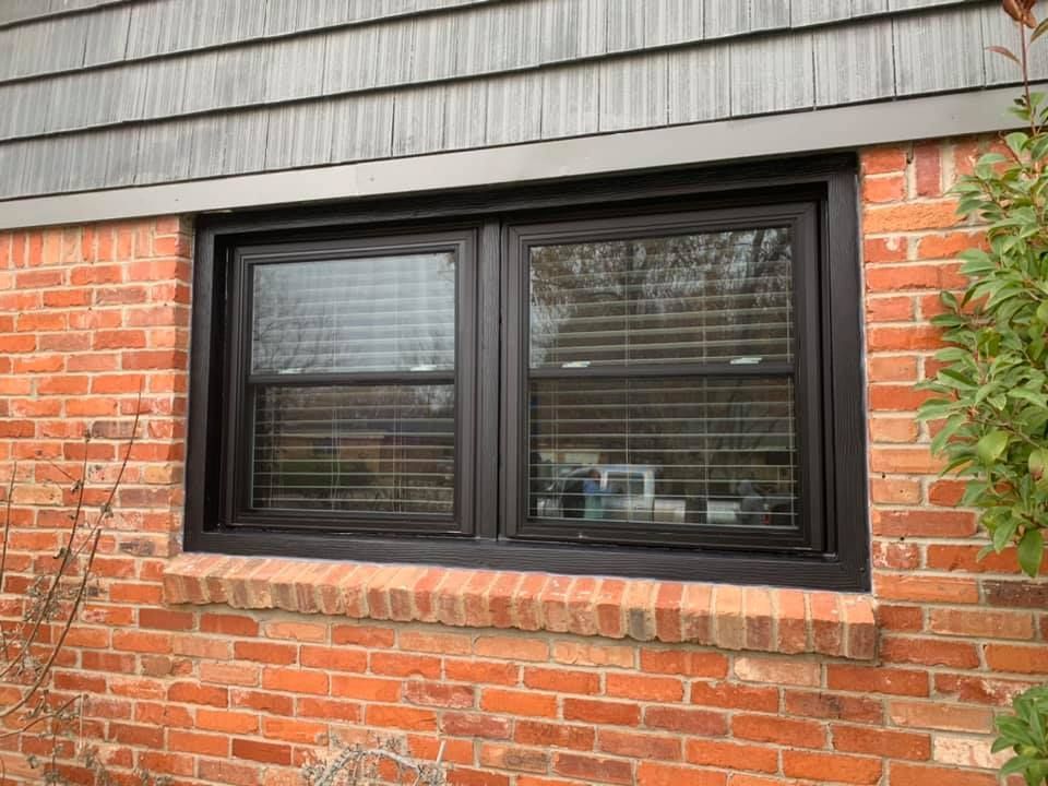 A brick wall with a black window on it.