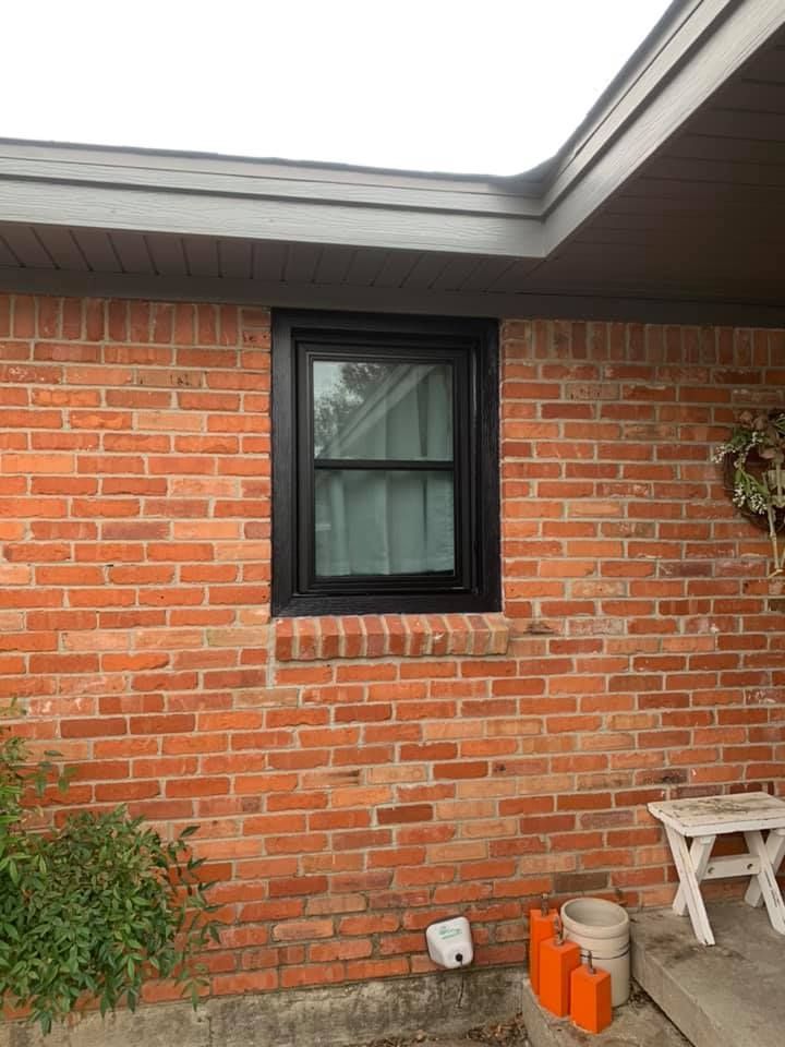 A brick wall with a black window on it.