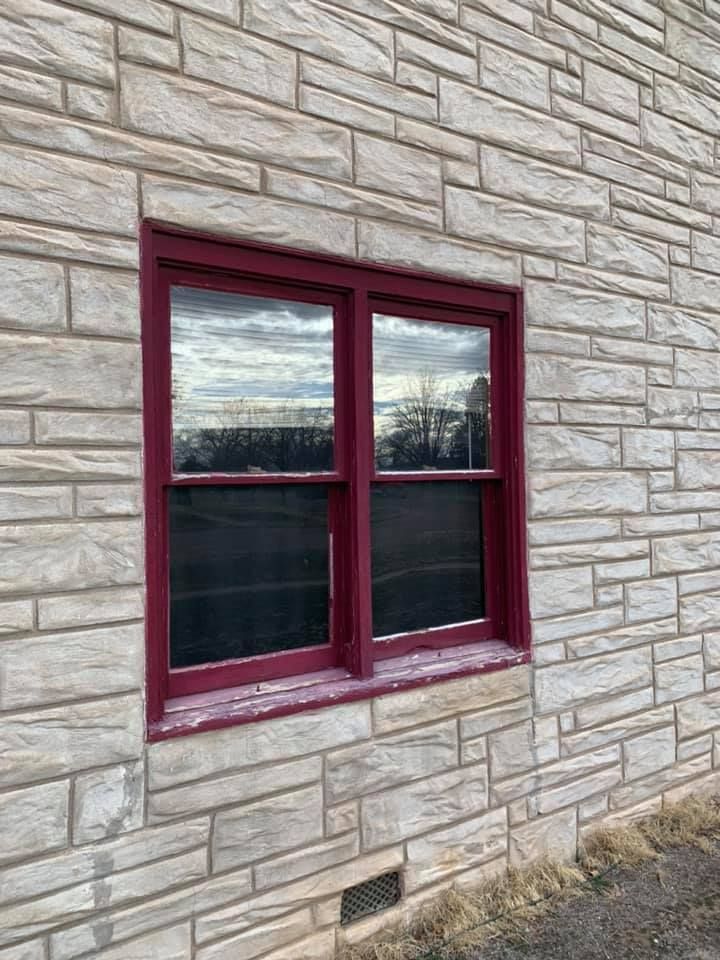 A brick wall with a red window on it.