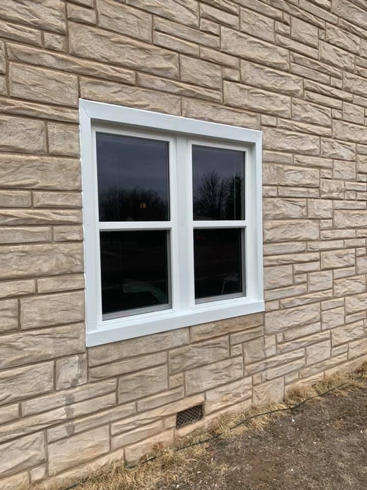 A white window is on the side of a brick building.