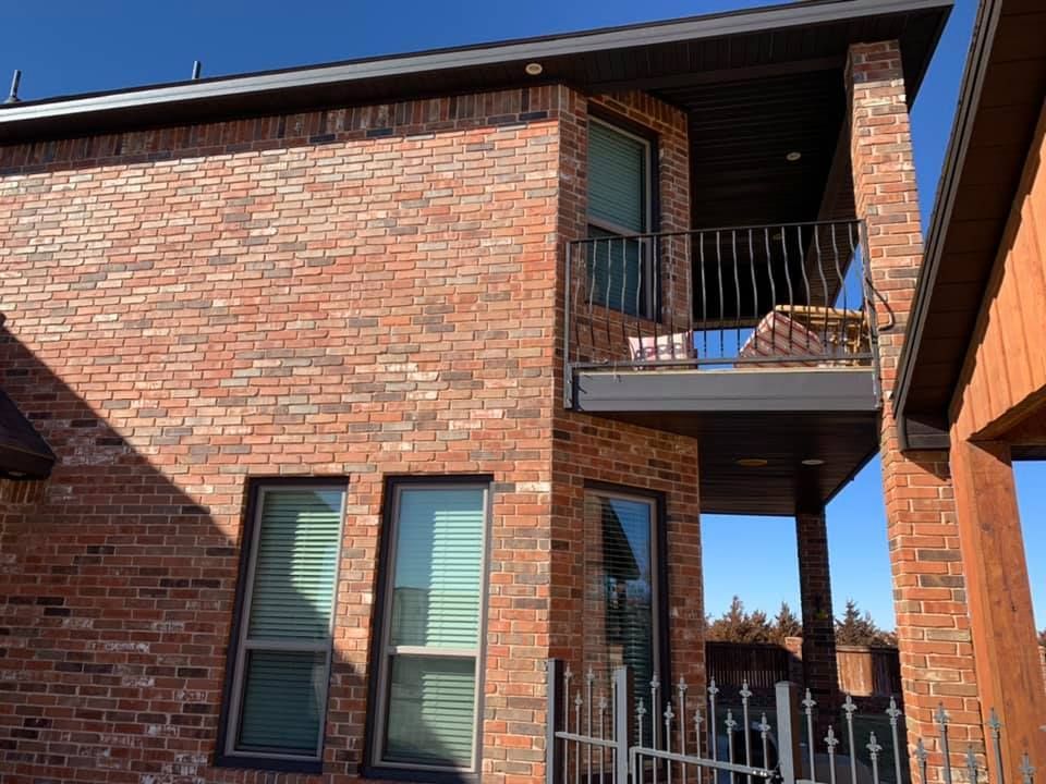 A brick house with a balcony and a fence in front of it.
