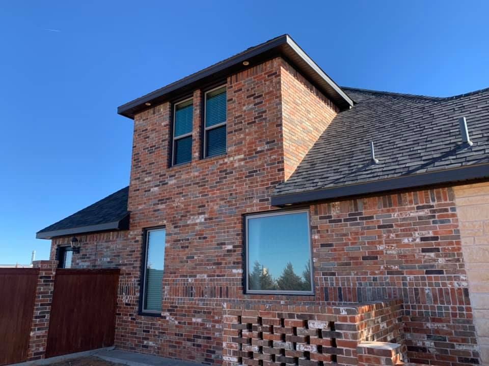 A brick house with a roof and a lot of windows