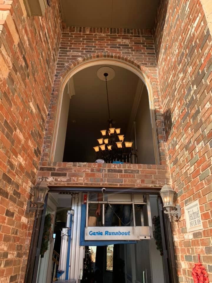 A brick building with a large archway and a chandelier hanging from the ceiling.