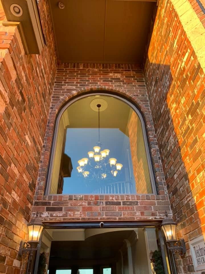 A brick building with a large window and a chandelier hanging from the ceiling.
