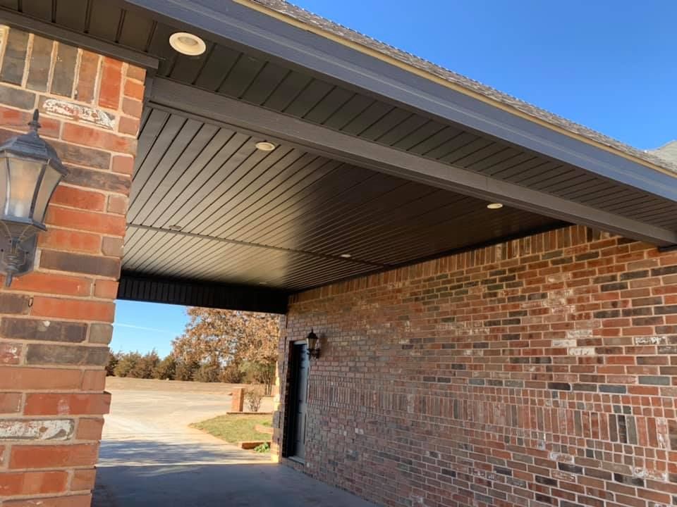 A brick building with a black roof and a lamp on the side.