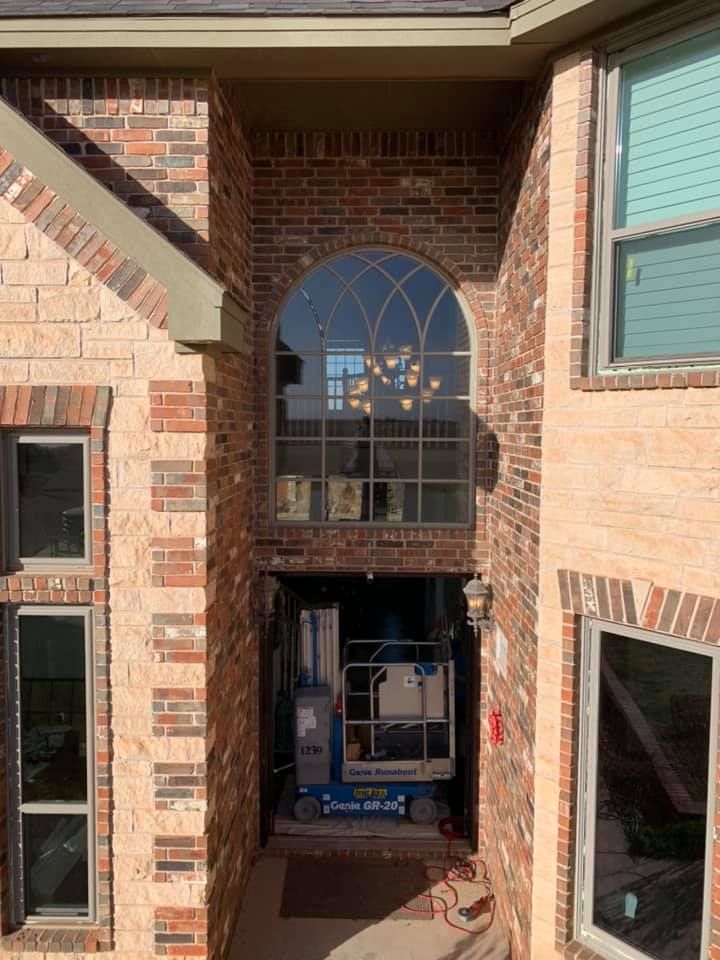 A brick building with a large arched window and a lift in front of it.