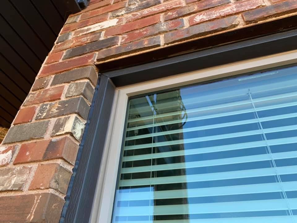 A close up of a window with blinds on a brick building.