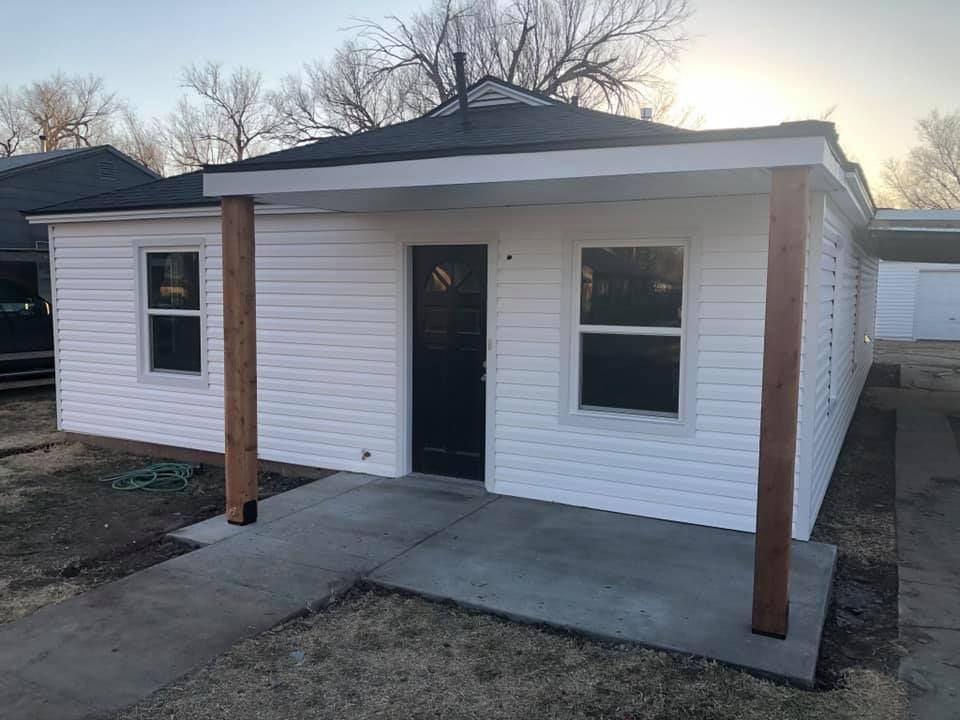 A small white house with a porch and a black door.