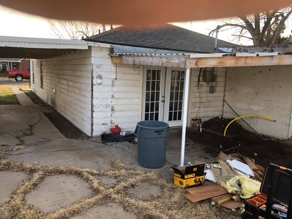 The backyard of a house with a trash can in front of it.