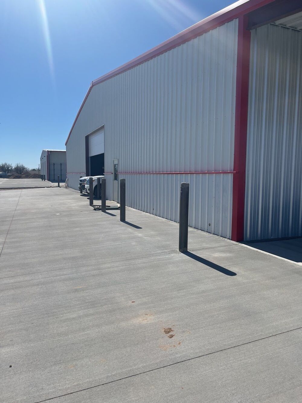 A large white building with a red trim and a concrete driveway in front of it.