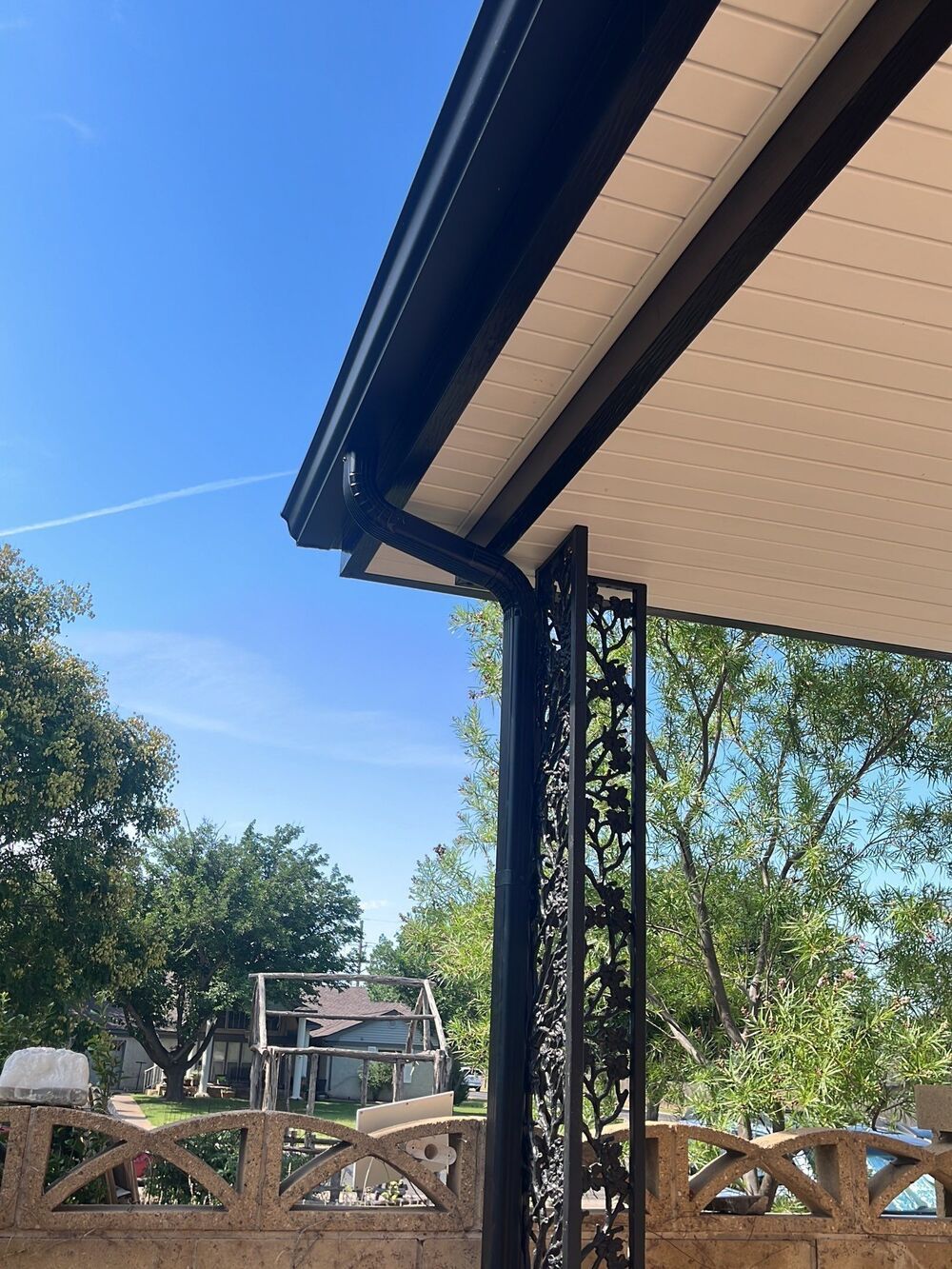 A gutter on a porch with a blue sky in the background.
