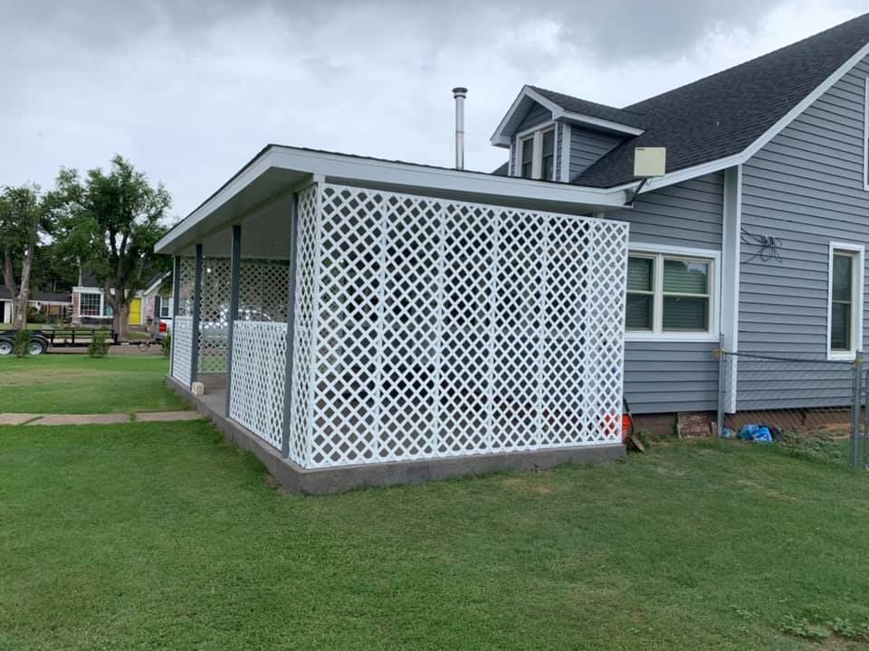 A house with a porch and a white lattice on the side of it.