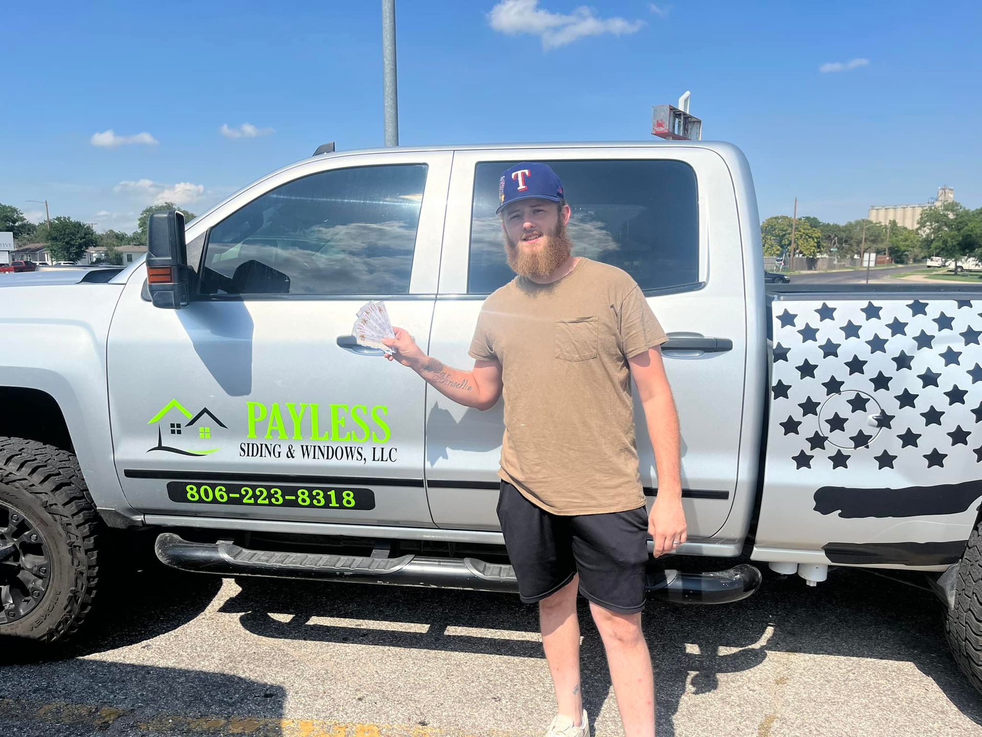 A man is standing in front of a truck in a parking lot.
