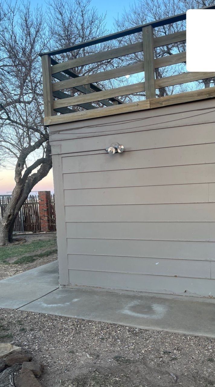 A gray building with a wooden deck on top of it.