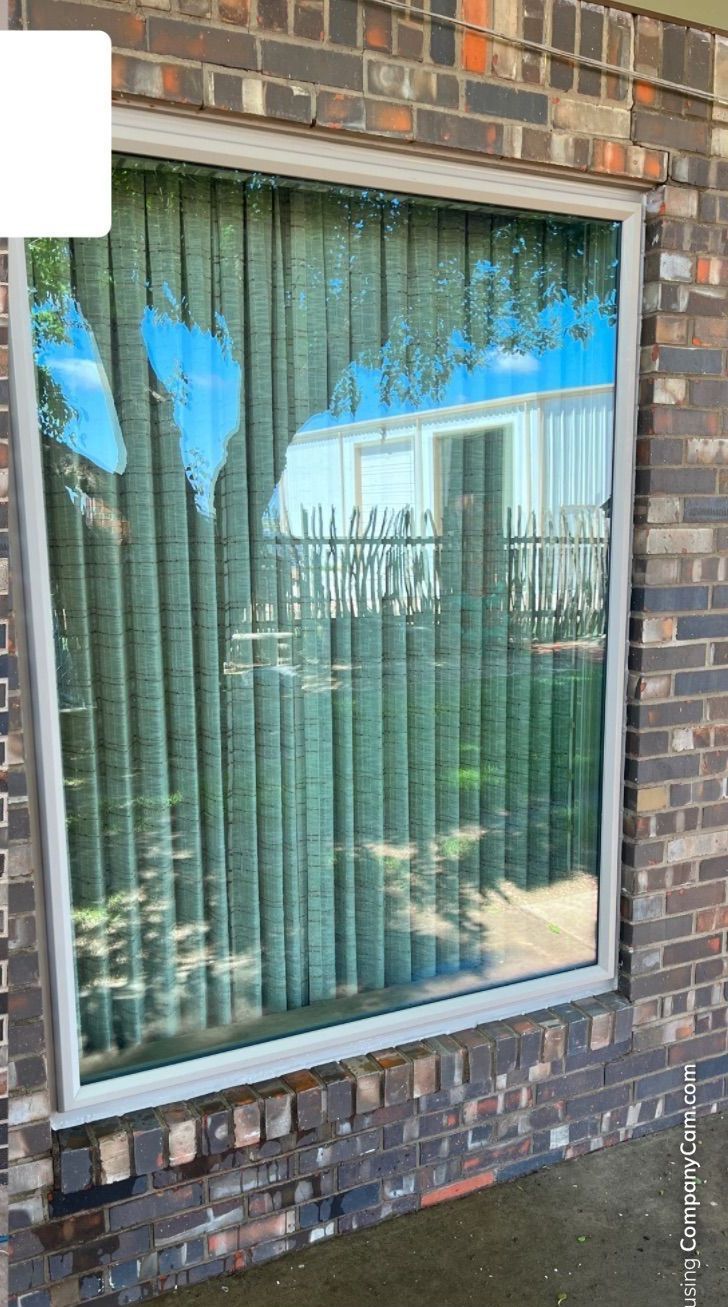 A window with vertical blinds on a brick wall.