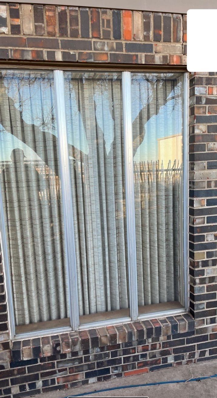A brick building with a window and curtains on it.