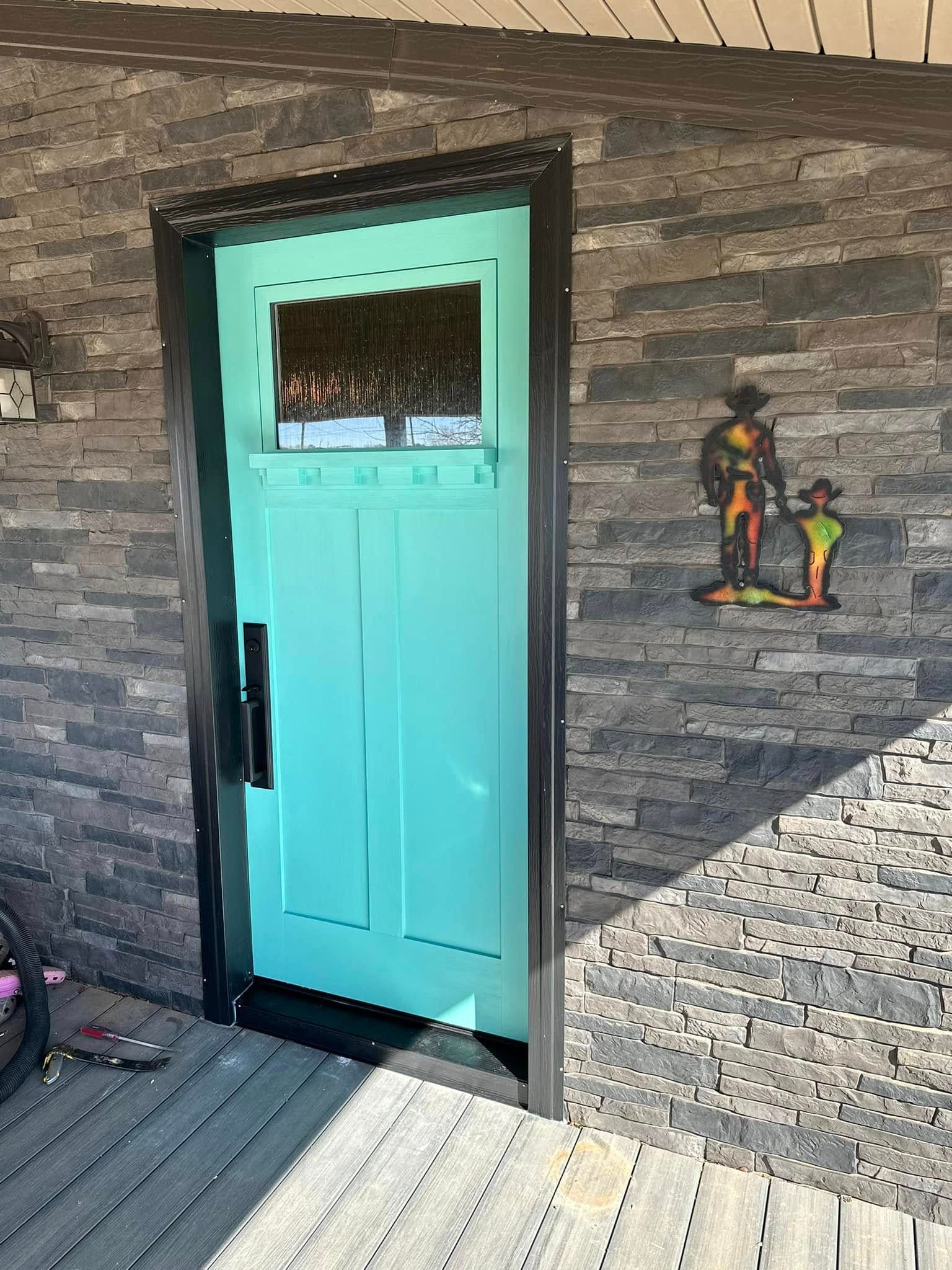 A blue door is sitting on a wooden porch next to a brick wall.