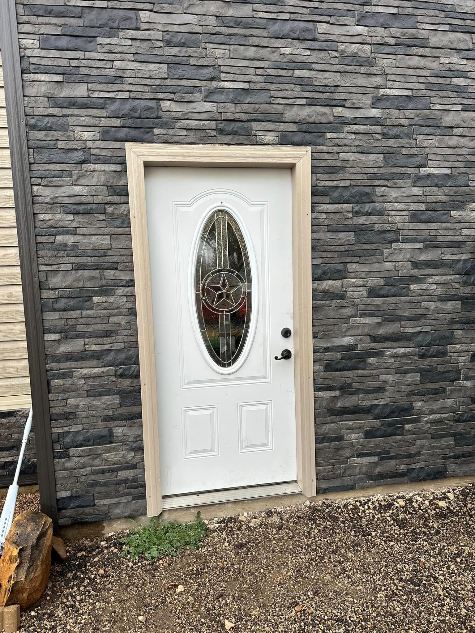 A white door with a glass window is on a brick wall.