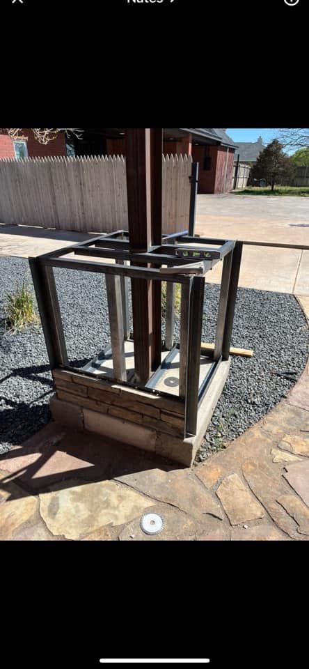 A metal structure is sitting on top of a gravel area next to a pole.