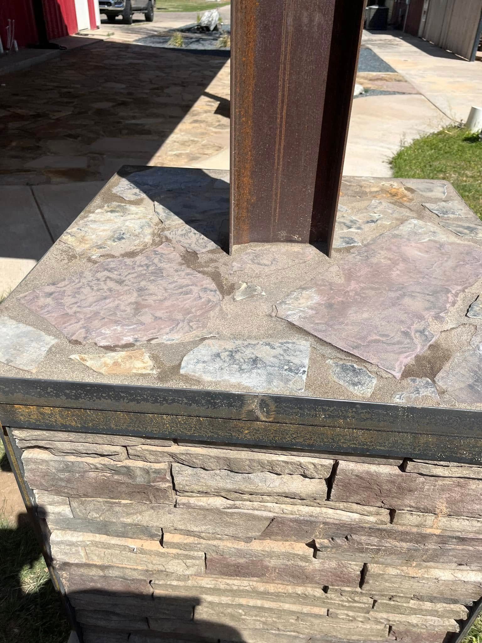 A metal pole is sitting on top of a stone wall.