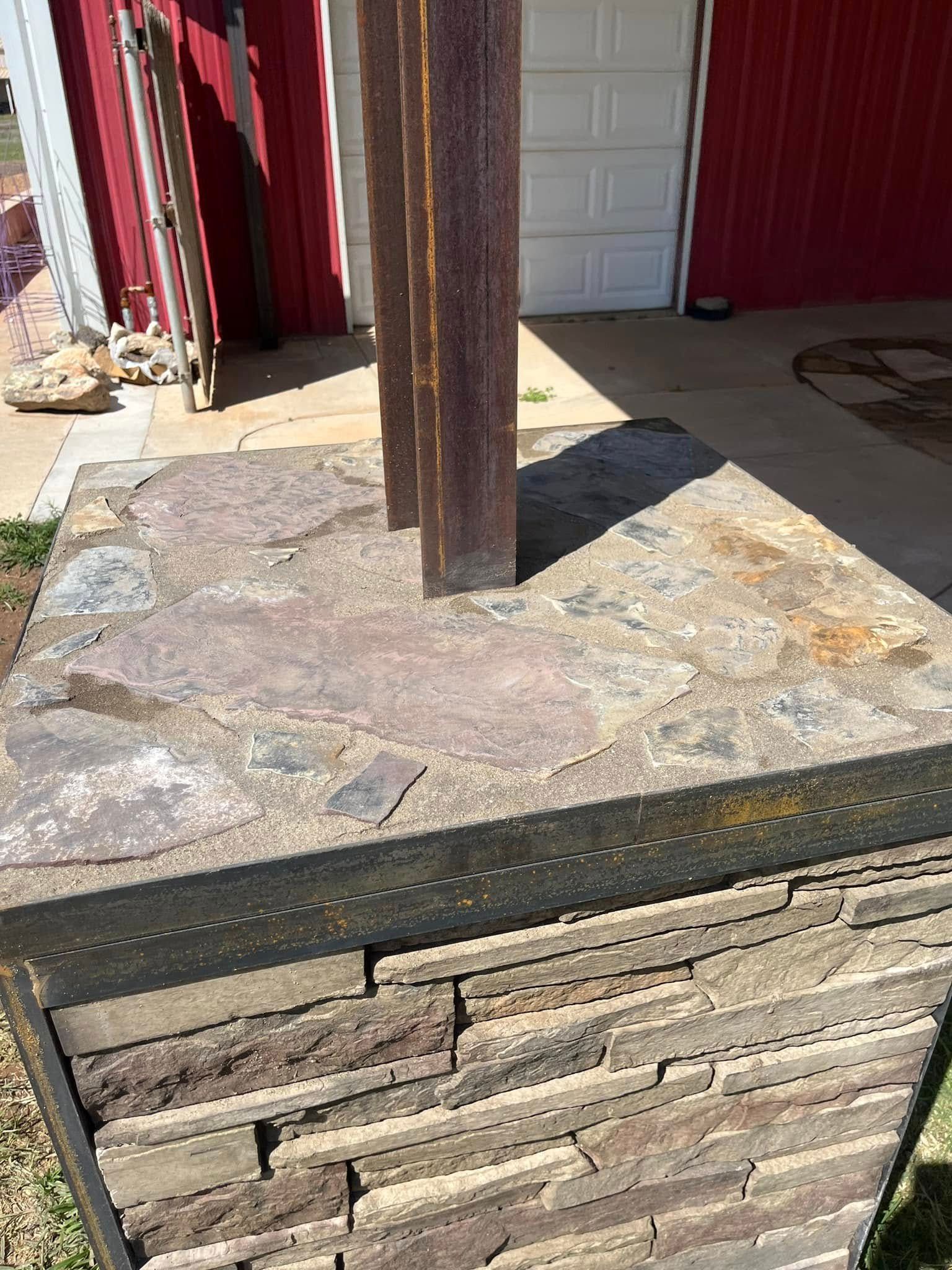 A metal pole is sitting on top of a stone base in front of a red garage door.