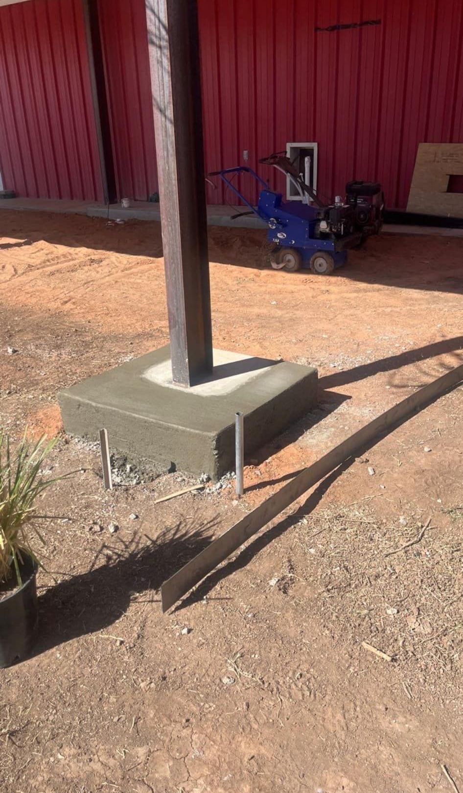 A blue toy tractor is parked in front of a red building.