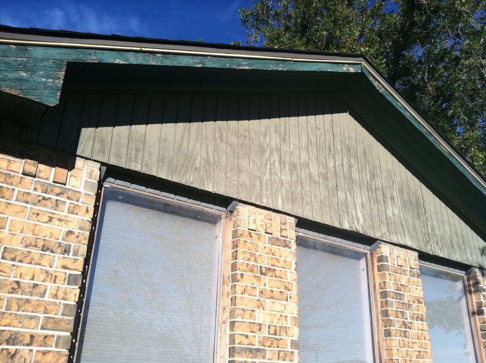 A brick building with a green roof and white windows