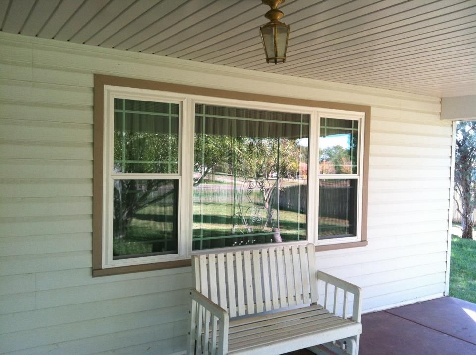 A porch with a bench and a large window