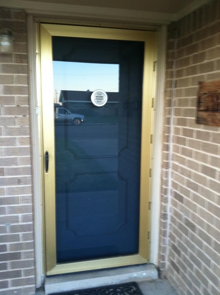 A black door with a gold frame is on a brick wall