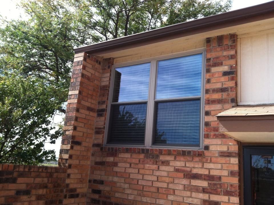 A brick building with a window and a tree in the background