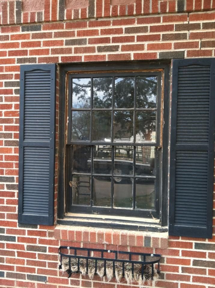 A window with black shutters on a brick wall