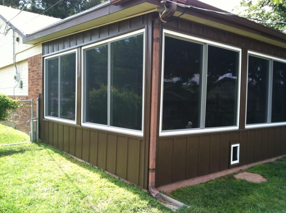 A screened in porch with a lot of windows on the side of a house.