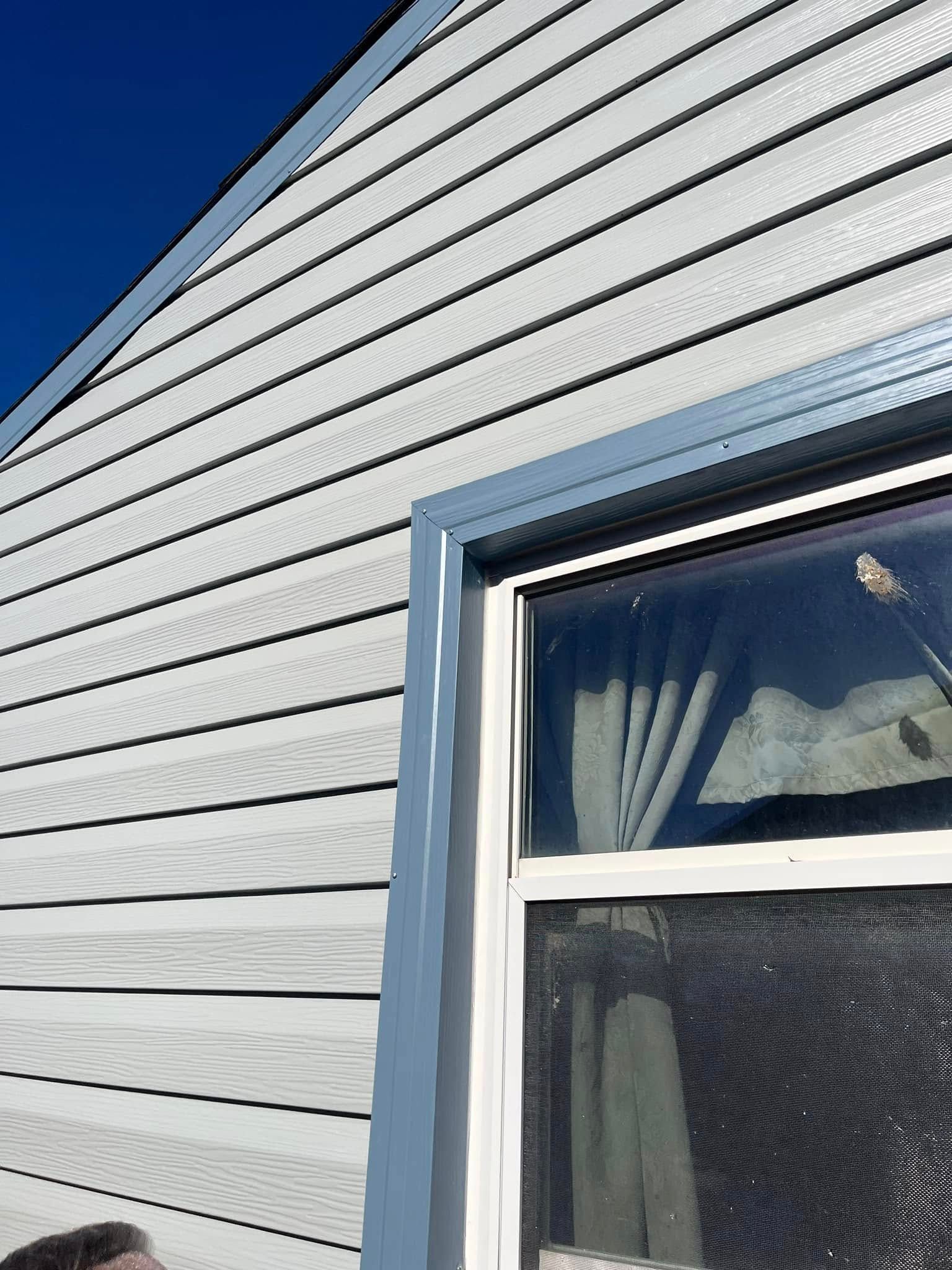 A man is standing in front of a window on the side of a house.