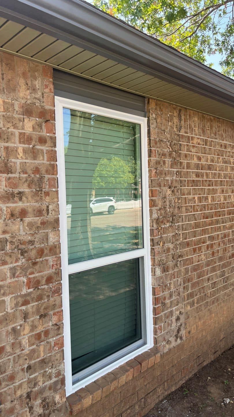 A brick house with a white window on the side of it.