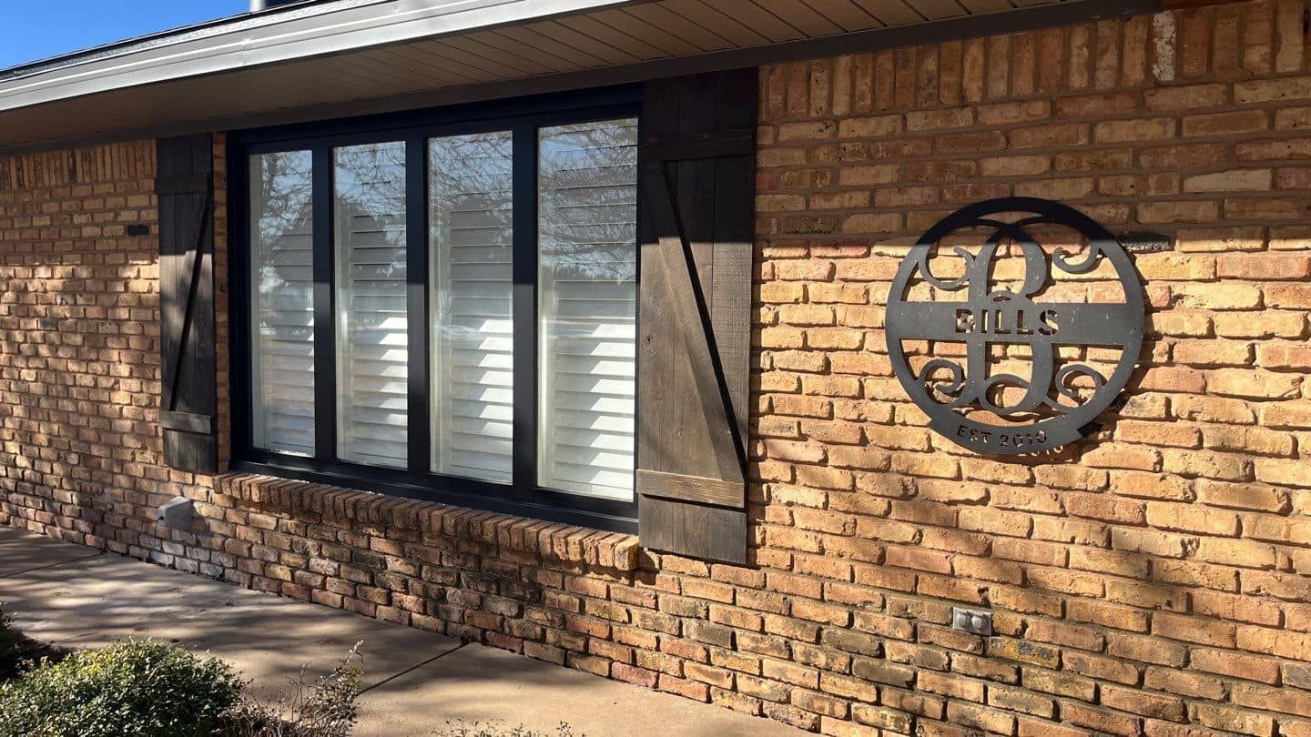 A brick house with a large window and a monogram on the side of it.