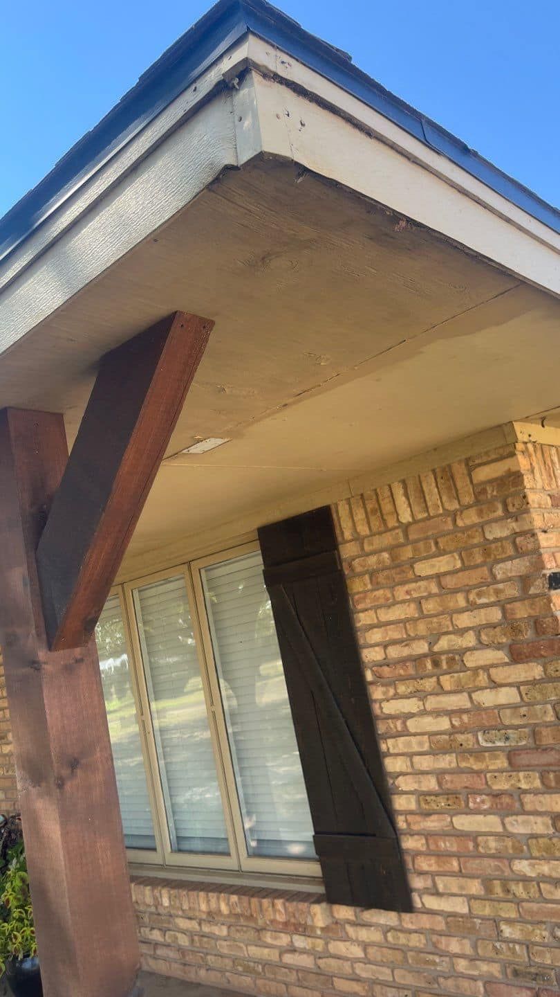 A brick house with a porch and shutters on the windows.
