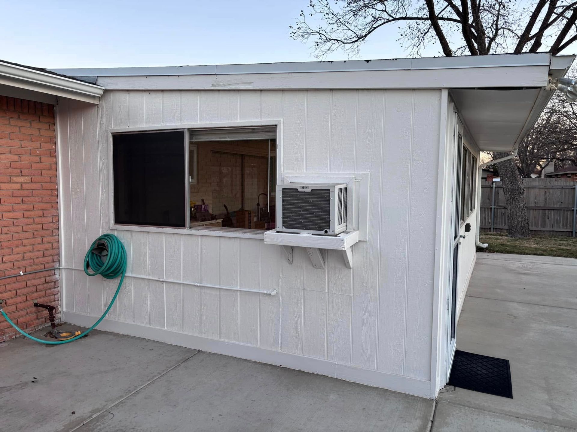 A small white building with a window and air conditioner on the side.
