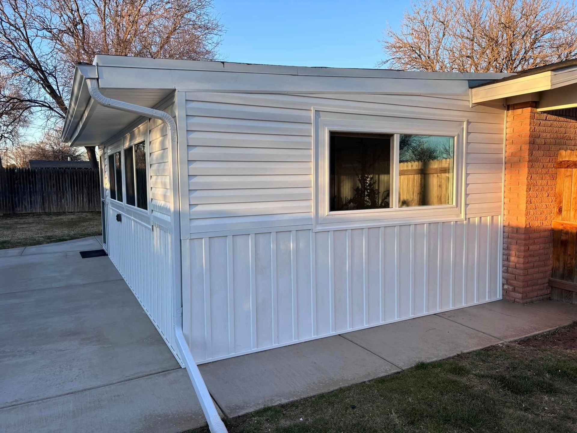 A white mobile home with a large window on the side of it.