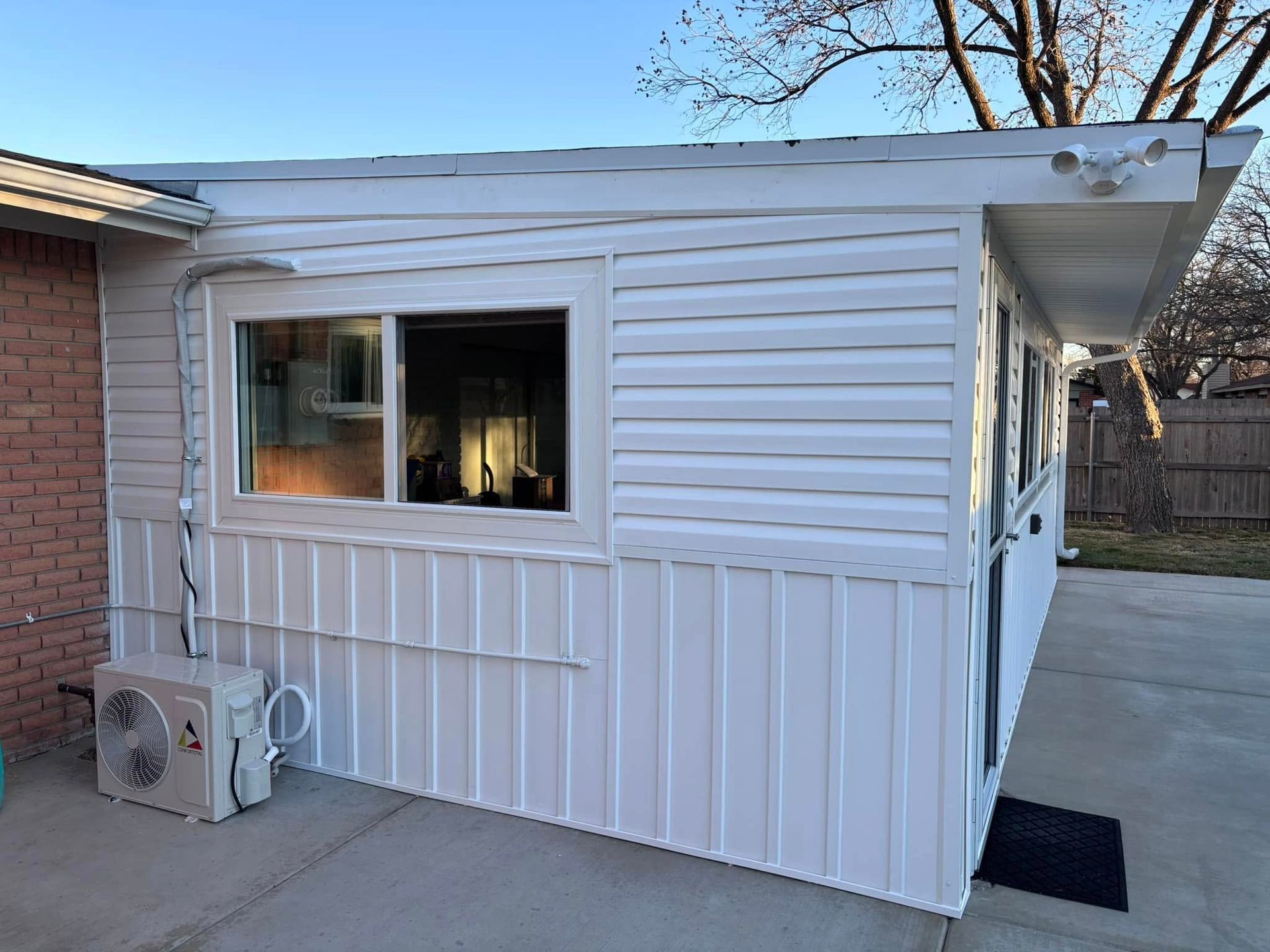 A white house with a window and air conditioners on the side of it.