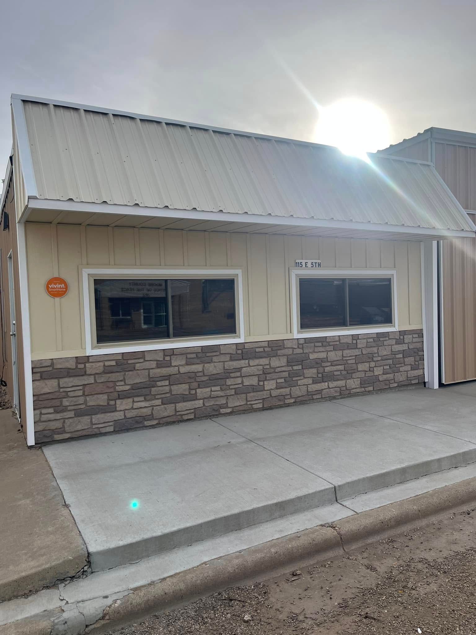 A small building with a metal roof and a stone wall.