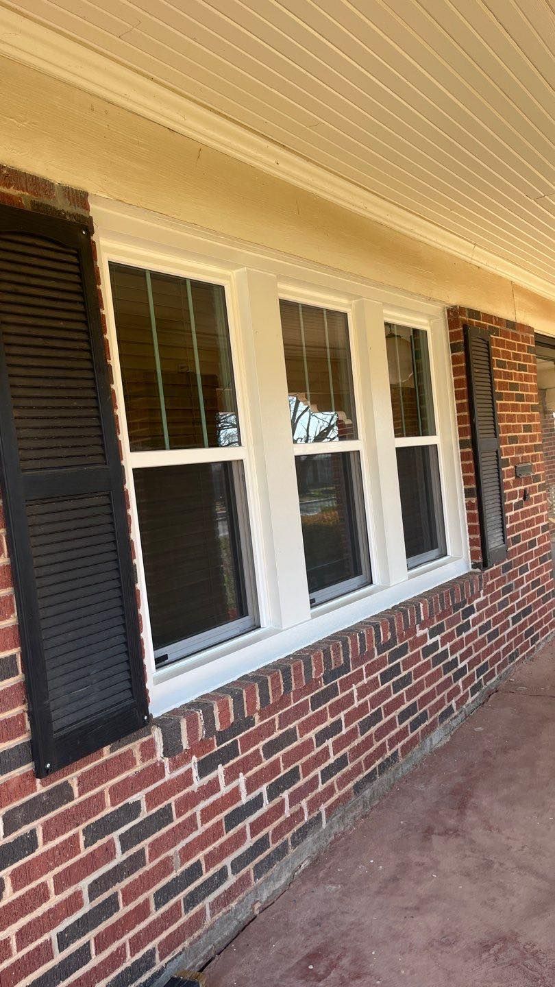 A brick house with white windows and black shutters.
