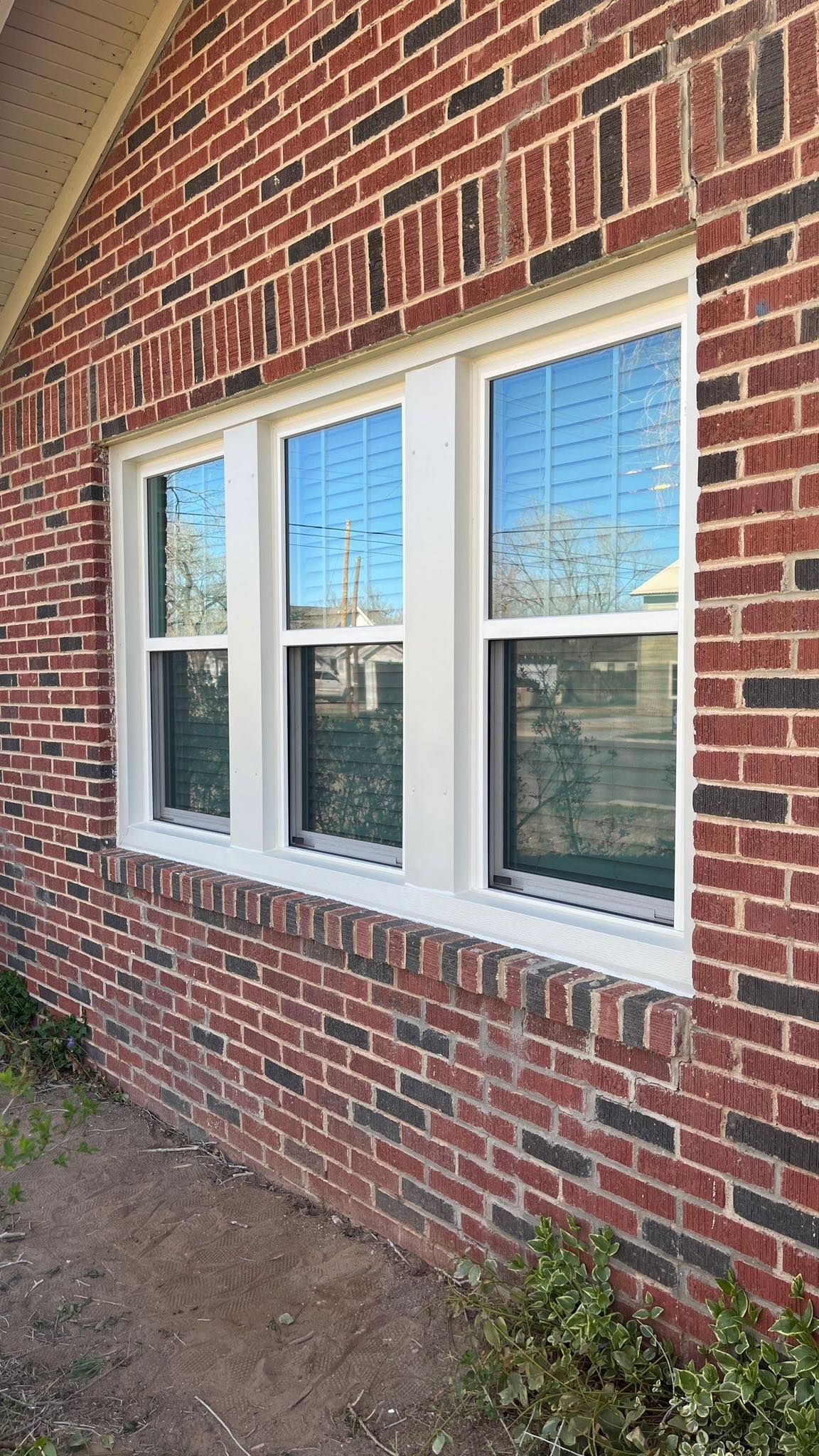 There are three windows on the side of a brick building.