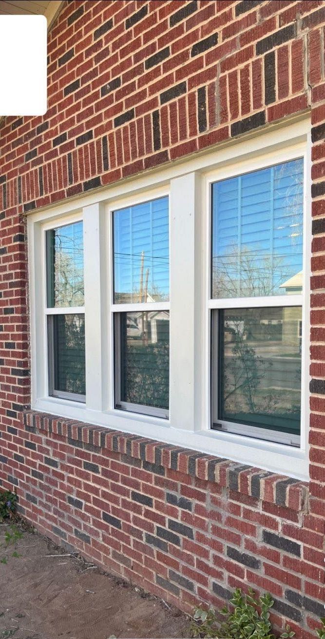 There are three windows on the side of a brick building.