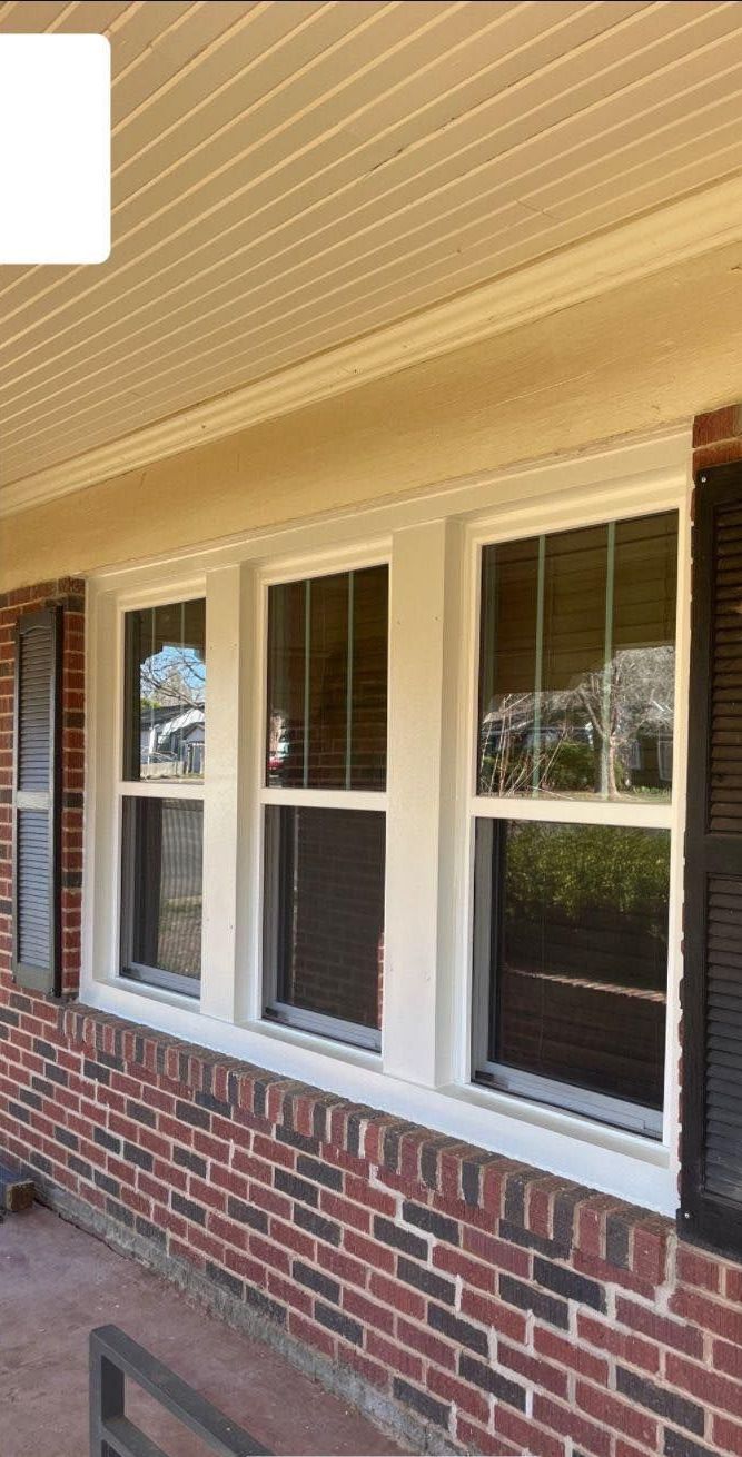 A brick house with white windows and black shutters.